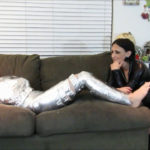 Young barefoot girl tape gagged in mummification bondage