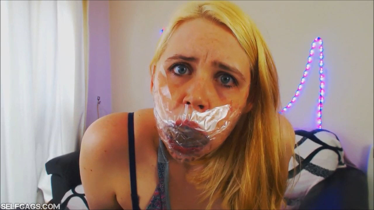Girl gagged with pantyhose behind clear tape gag