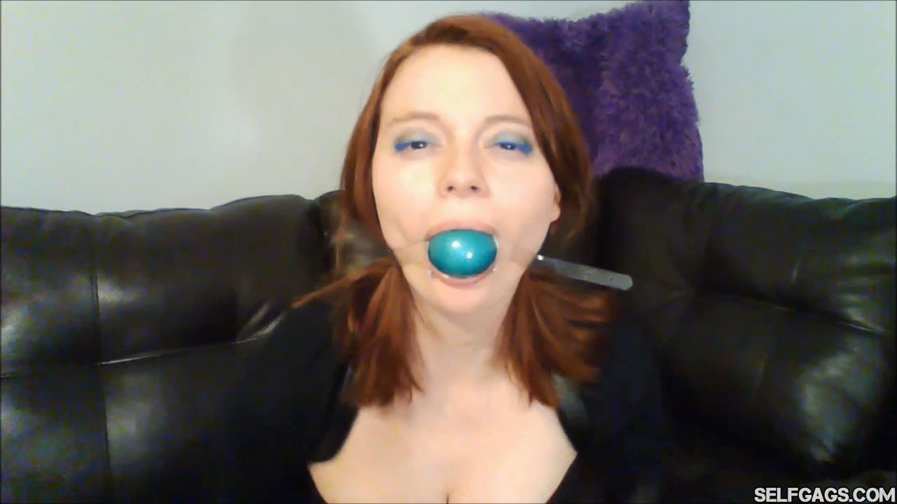Redheaded girl gagged with light blue ballgag