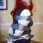Sexy redhead gagged in tape bondage