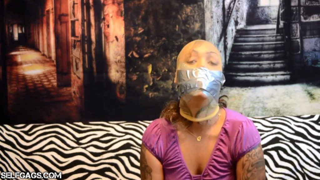 Self-gagged latina has duct tape wrapped around her pantyhose encased head