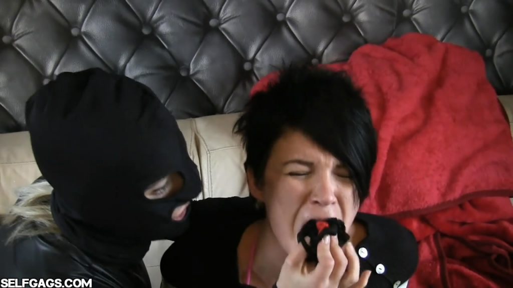 Dirty panties stuffed inside girls mouth by a masked woman in a leather catsuit