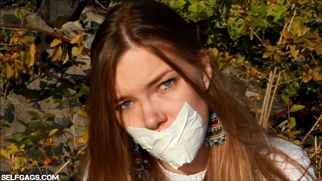 Tape gagged girl is helpless outdoors