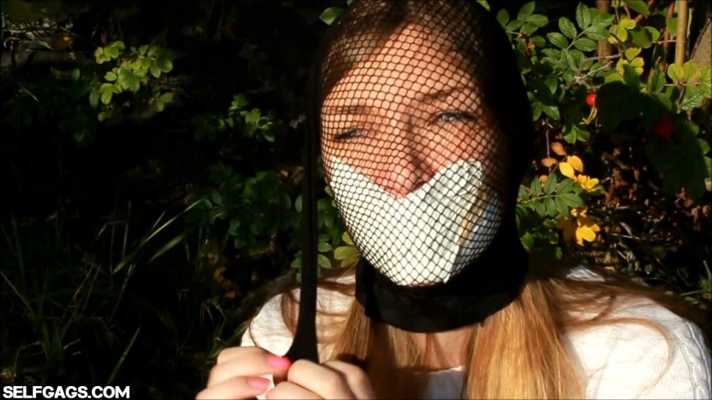 Tape gagged model head encased with fishnet pantyhose outdoors