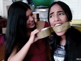 Sexy girl with dark hair gets tape wrap gagged by best friend in bondage