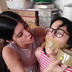 Nerdy girl gagged with tape wrapped around head in tight lesbian tape bondage