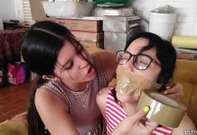 Nerdy girl gagged with tape wrapped around head in tight lesbian tape bondage