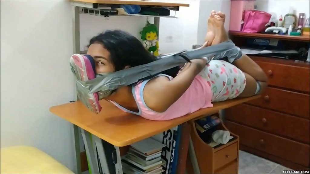 sexy latina babysitter gagged and hogtied barefoot with duct tape on table with stinky running shoe tied to her face