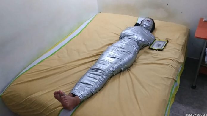 Barefoot girl gagged and blindfolded in mummification bondage
