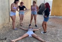 Young woman in outdoor bondage is tied spreadeagle on the ground by four dominant women