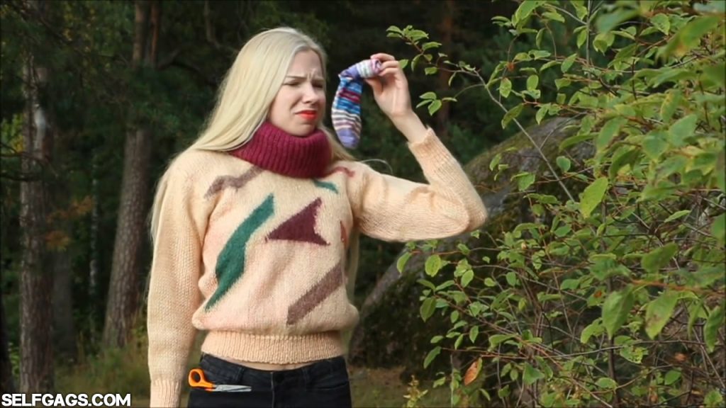 Blonde sweater girl self-gagged in forest