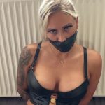 Blonde woman gagged with black tape in leather lingerie