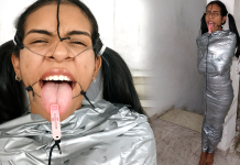 BDSM girl mummified with duct tape with clothespin on her tongue. She is wearing a open mouth gag