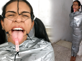 BDSM girl mummified with duct tape with clothespin on her tongue. She is wearing a open mouth gag