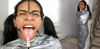 Mummified In The Name Of Art – Selfgags BDSM girl mummified with duct tape with clothespin on her tongue. She is wearing a open mouth gag