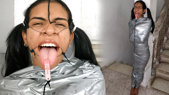 BDSM girl mummified with duct tape with clothespin on her tongue. She is wearing a open mouth gag
