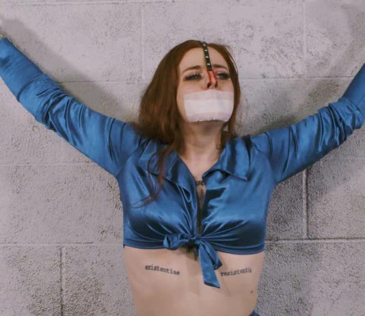 Freshie Juice Gagged & Nose-Hooked for Game Day Control Handcuffed girl with red hair is wearing a medical tape gag and a nose hook pulling her nose upwards