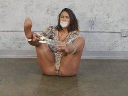 Gagged woman locked in cuffs wearing pantyhose and snakeskin clothes