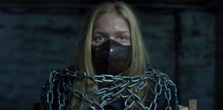 Bound Beauty Everly: Shackled, Gagged, and Helpless in Leather Blonde teen Everly, muzzled with a thick brown leather BDSM gag, heavily shackled in steel chains, wearing a black leather jacket, sitting helplessly in a dark basement.