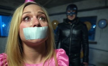 Terrified Birthday Girl Gagged, Facing Sadistic Punishment An 18-year-old birthday girl in a pink dress and party hat, duct tape gagged with tears streaming. A leather-clad sadist with a whip looms ominously.
