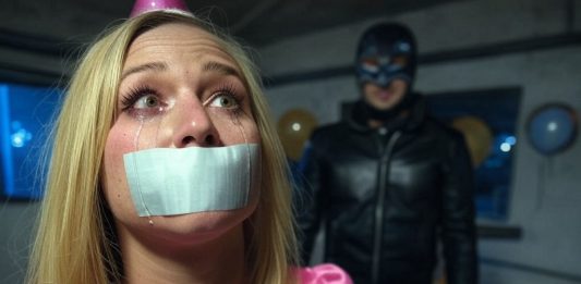Terrified Birthday Girl Gagged, Facing Sadistic Punishment An 18-year-old birthday girl in a pink dress and party hat, duct tape gagged with tears streaming. A leather-clad sadist with a whip looms ominously.