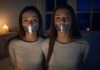 Two Brunette Sisters Tape Gagged in Candlelit Bedroom Two brunette sisters, around 19 years old, tape gagged and tied, sitting on a bed in a candlelit bedroom, gazing at the viewer with seductive expressions.