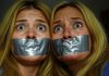 40-year-old American blonde mom and 20-year-old blonde daughter, duct tape gagged with arms tied, distressed eyes, in a dim room setting.