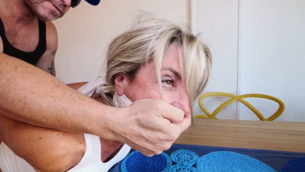 Terrified Elenoire Steiner in white crop top gets roughly hand-gagged over her thick white cleave gag by fugitive Tony Houston, eyes wide with fear as he clamps his hand brutally tight across her already stuffed and gagged mouth – Tony Houston Bondage Paranoia intense double-gagging domination