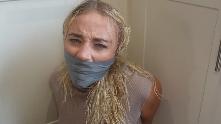 Close-up of angry Zoey Ziptie gagged with layers of tape.