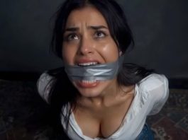 Brunette Duct Tape Cleave Gagged & Struggling Helplessly on Floor – AI Bondage Woman with duct tape over her mouth, looking upward with a distressed expression in a dim room.