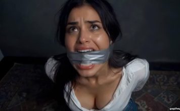 Brunette Duct Tape Cleave Gagged & Struggling Helplessly on Floor – AI Bondage Woman with duct tape over her mouth, looking upward with a distressed expression in a dim room.