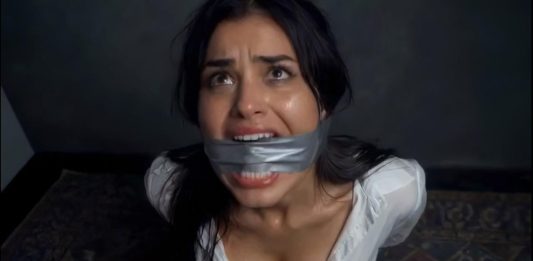 Brunette Duct Tape Cleave Gagged & Struggling Helplessly on Floor – AI Bondage Woman with duct tape over her mouth, looking upward with a distressed expression in a dim room.