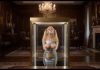 Missing Teacher Julie Millard Duct Taped & Displayed in Billionaire’s Glass Case – AI Bondage Wide shot of the glass display case elevating with bound and gagged teacher Julie Millard inside opulent room