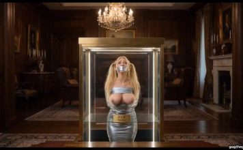 Missing Teacher Julie Millard Duct Taped & Displayed in Billionaire’s Glass Case – AI Bondage Wide shot of the glass display case elevating with bound and gagged teacher Julie Millard inside opulent room