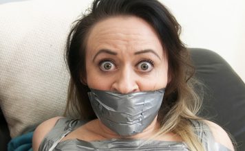 Why Men Find Tape-Gagged Women So Attractive Brunette woman with wide eyes tightly gagged with multiple layers of silver duct tape covering her mouth and lower face