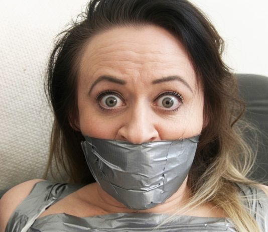 Why Men Find Tape-Gagged Women So Attractive Brunette woman with wide eyes tightly gagged with multiple layers of silver duct tape covering her mouth and lower face