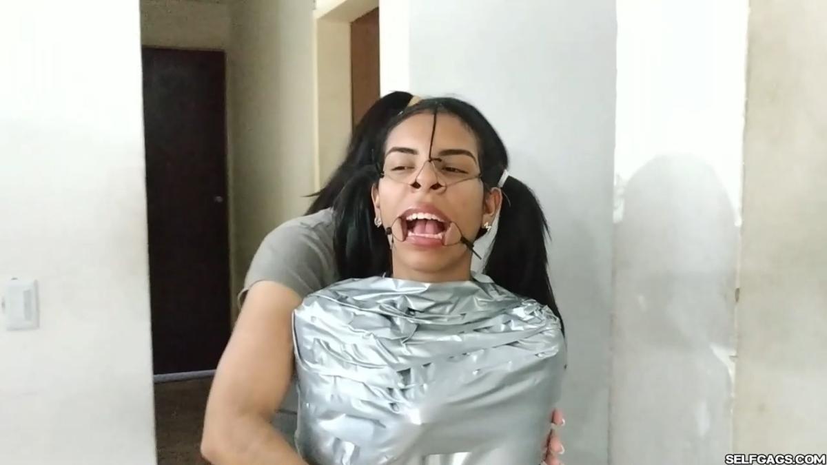 Cute girl gets duct tape mummified BDSM training by female bondage photographer