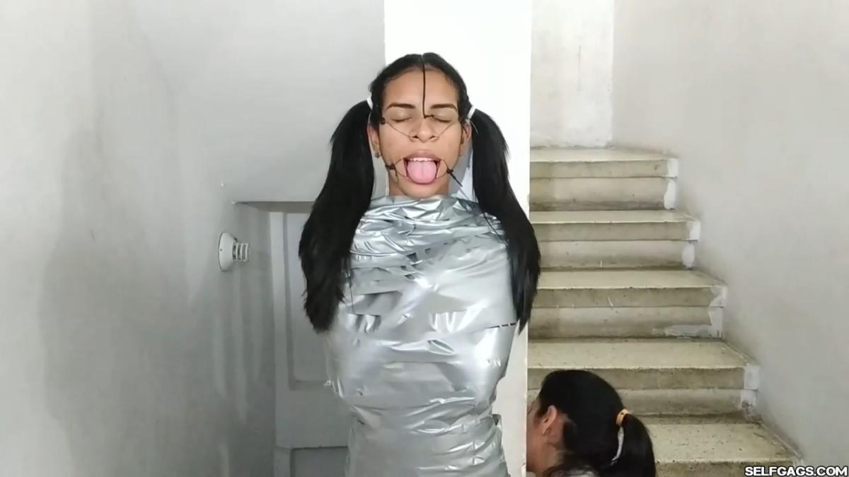 Cute girl gets duct tape mummified BDSM training by female bondage photographer