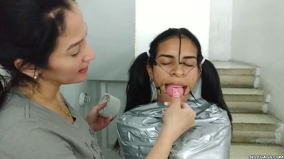 Cute girl gets duct tape mummified BDSM training by female bondage photographer