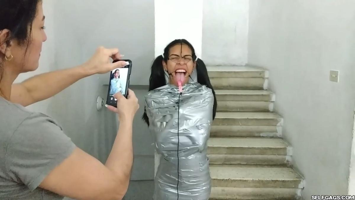 Cute girl gets duct tape mummified BDSM training by female bondage photographer