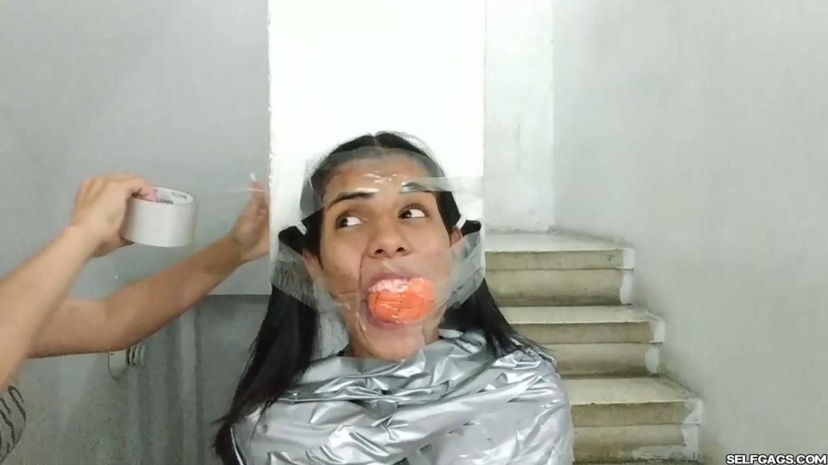 Cute girl gets duct tape mummified BDSM training by female bondage photographer