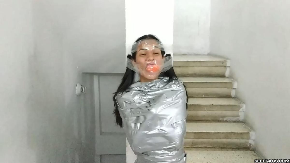 Cute girl gets duct tape mummified BDSM training by female bondage photographer