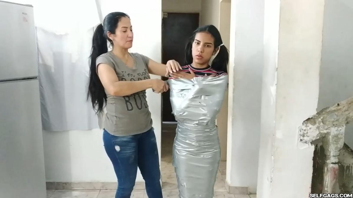 Cute girl gets duct tape mummified BDSM training by female bondage photographer