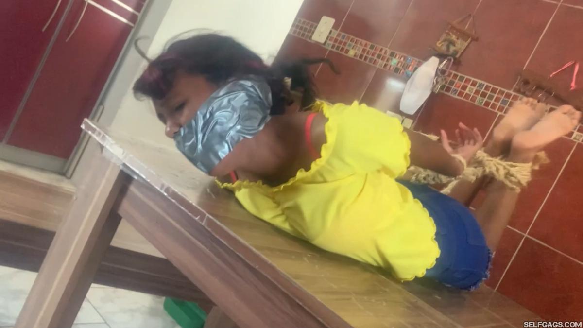 Barefoot girl gagged and hog-tied on table