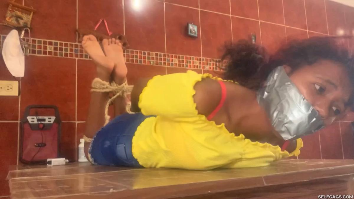 Barefoot girl gagged and hog-tied on table