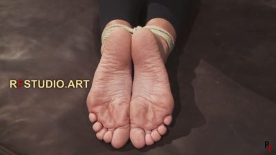 Close-up of Lali's bare soles with white rope wrapping her ankles