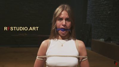 Frontal medium of Lali in reverse prayer with the blue ball gag and rope harness