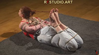 Rear view of Emily's hogtie showing bare soles and the rope joining ankles to wrists