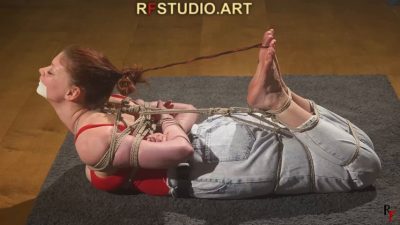 Side hogtie at full stretch — bare soles high, tape gag, jute chest harness