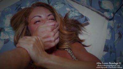 Handgag ambush — a tan hand clamps over Alba’s mouth on the floral bed while she wears a leopard top and reaches for the wrist